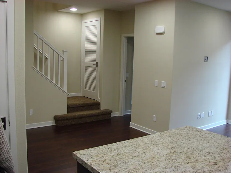View from kitchen looking at stairs to 3rd floor, washer/dryer cabinet, and door entrance to 2nd floor bedroom