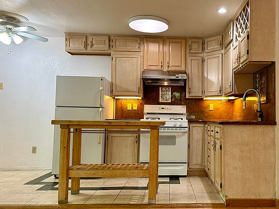 Open layout kitchen, living and dining areas with a ceiling fan.