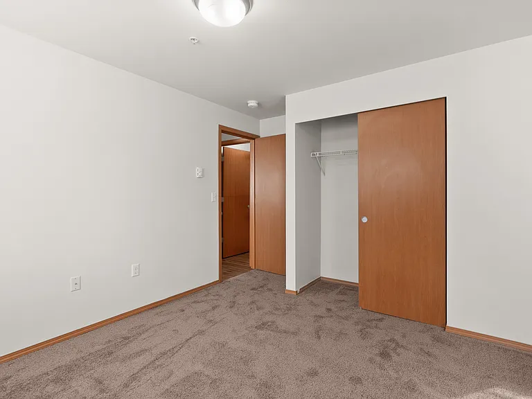 Inviting bedroom with plush carpet, ample closet space, and sleek wooden doors for a cozy living experience. Inviting bedroom with plush carpet, ample closet space, and sleek wooden doors for a cozy living experience.