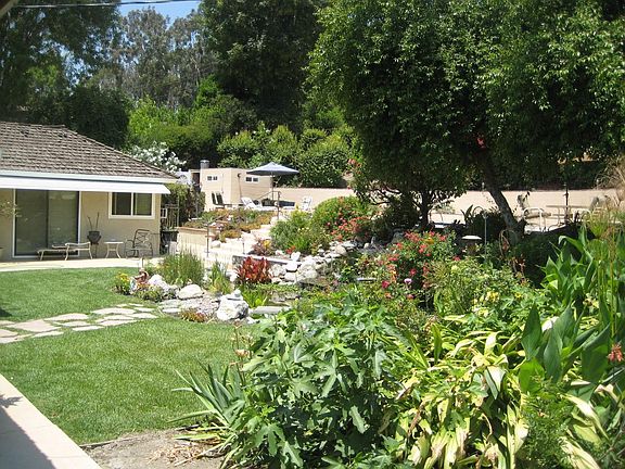 View of the back yard. Large swimming pool on upper level at top of stairs