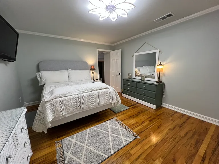 16x12 large bedroom. Queen bed with comfy topper. Loads of king pillows. Cushioned headboard. Full length mirror. Wall mounted 42 inch Vizio smart TV. Two dressers with lots of drawers. LED ceiling light with fan. Hardwood floors with lovely rugs. Lamps.