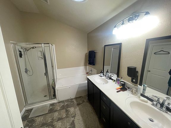 Primary Bath with sky light, jetted tub, shower, and double vanity