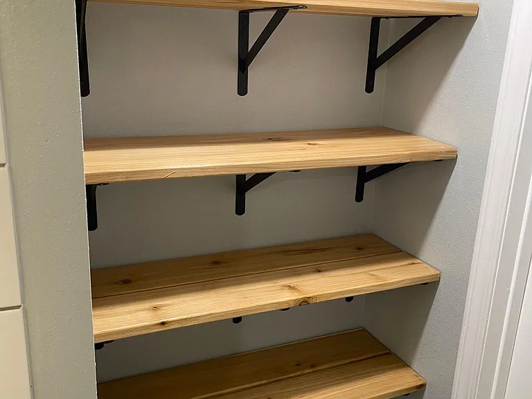 Custom linen closet with more oil rubbed designer shelves and steel brackets reduce the need for more furniture