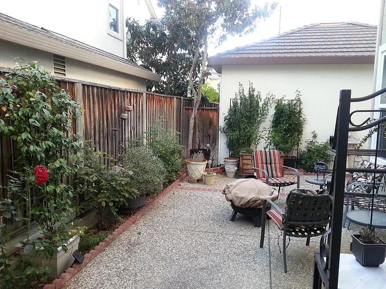 A quiet, shaded backyard retreat perfect for relaxing and gardening, complete with blooming roses and dedicated space for planting your own fresh vegetables. A peaceful outdoor escape to unwind and enjoy your morning coffee.
