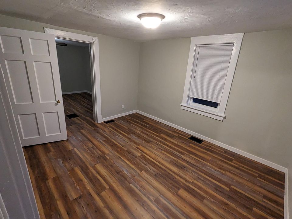 Living room with bedroom through the back wall and bathroom through open door on top left. Picture taken while standing in doorway to kitchen.