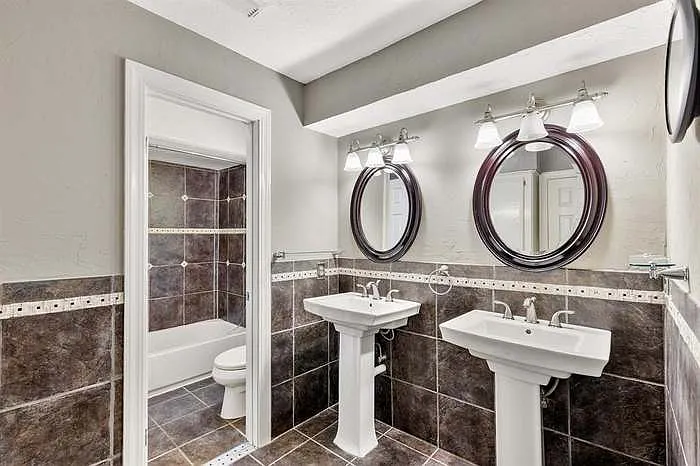Common full bathroom with double sinks and builtin storage.