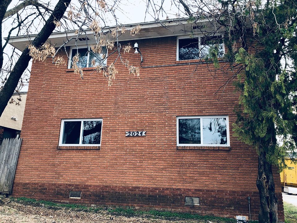 Brick building with new windows and mature tree, security camera
