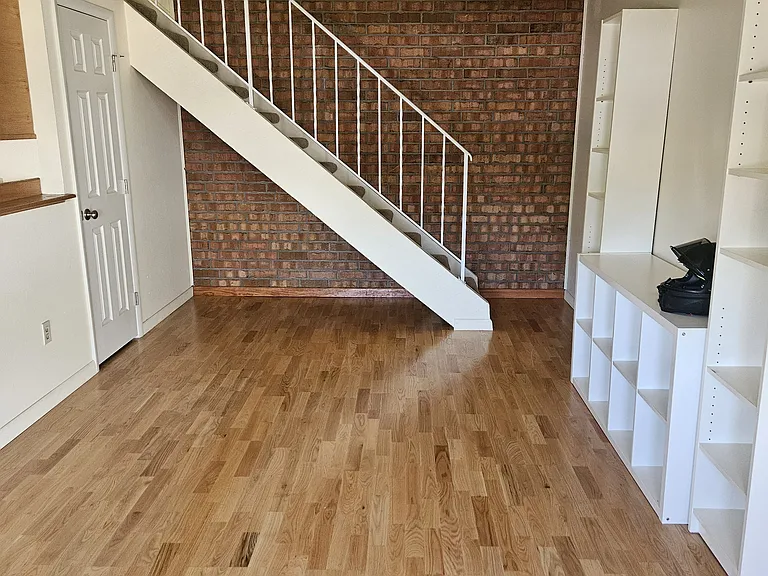 Family Room and stairs to the 2 beds and 1 bath upstairs. Natural brick exposed, hardwood flooring