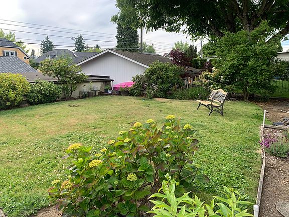 Big backyard with colorful shrubs and trees surrounding.