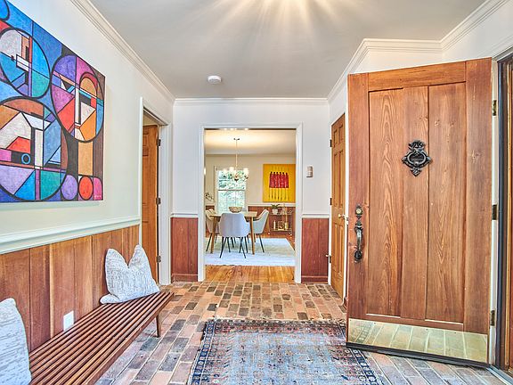 The front entry features a stately solid wood door, brick floors, and a coat closet.