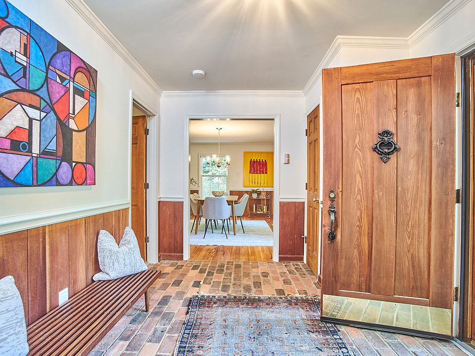 The front entry features a stately solid wood door, brick floors, and a coat closet.