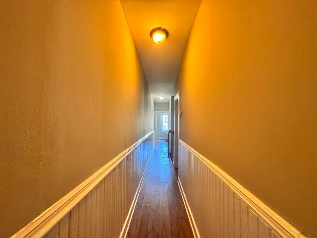 Hallway to the next bedroom and further to the kitchen as well as going upstairs for three more bedrooms.
