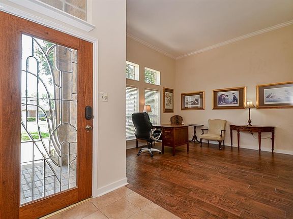 Your guests will enter through this welcoming entry door with leaded glass details. Note the stunning wood-look tile flooring that flows through the home along with the stylish crown molding.