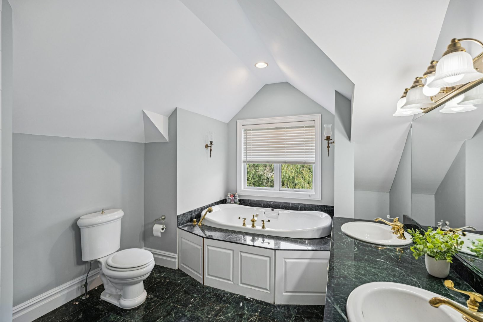The primary bath showcasinga whirlpool jetted tub, ambient recessed lighting, and double vanity.