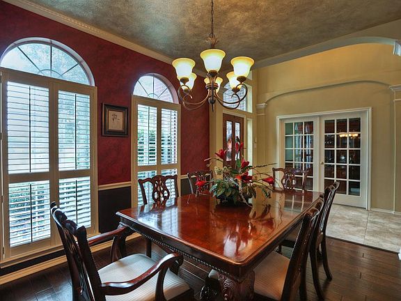 The DINING ROOM 13x11 is located off the wide entry Foyer. The room features wood flooring, an iron chandelier, Plantation shutters covering tall arched topped windows, wainscotting and designer paint.