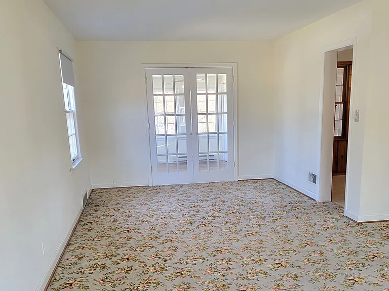 Living room with French doors into the 1st floor bedroom #1 with beautiful flower carpet