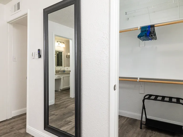 Relax in the primary bedroom featuring a luxurious king-size bed, full-body mirror, flat-screen Roku TV and an attached bathroom for your convenience. Don't forget the luggage carrier and hangers in the large, walk-in closet!