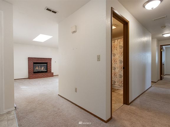 Entry leads to hallway and view of  wood burning brick fireplace