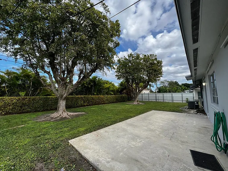 Big backyard with trees and patio area for family gatherings.