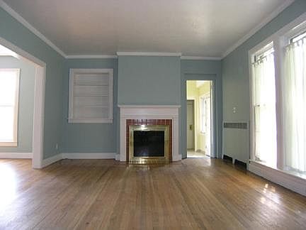 Living area with large windows, hardwood floors and built in bookcase. Fireplace is ornamental only.