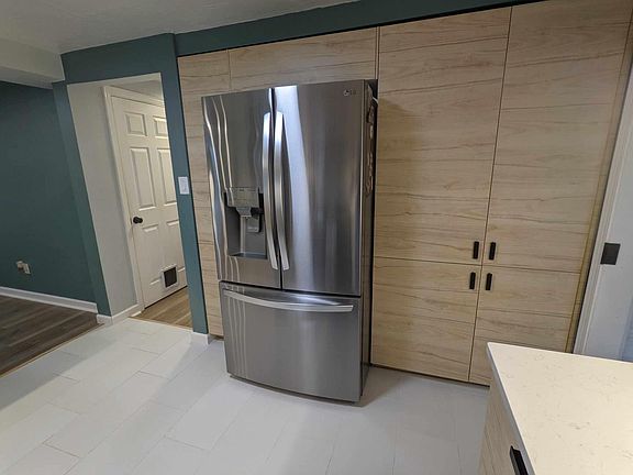 Full wall of pantry surrounding refrigerator with water and ice on door and cocktail ice in the freezer. Microwave hidden in pantry