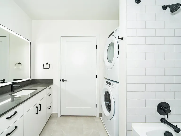 Bathroom with a clean-lined vanity, integrated lighting, and in-home washer and dryer designed for comfort and everyday ease.