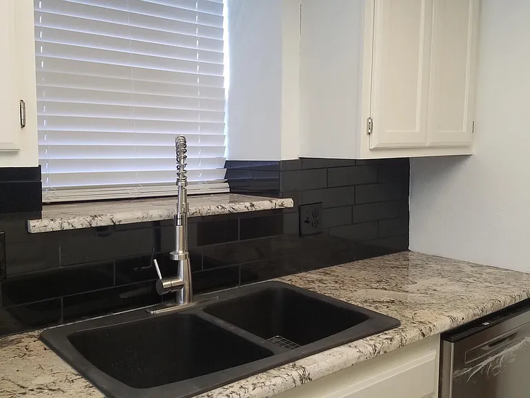 Black granite tile backsplace, granite countertops, New dishwasher new sink and faucet.