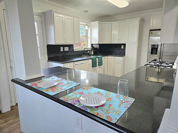 Modern kitchen with plenty of cabinet space, durable granite countertops, and a cozy bar for casual dining.
