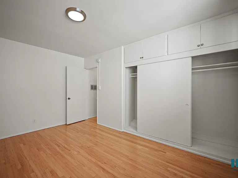 Bedroom with a Large-Size Closet, Cabinet Storage, and Hardwood Flooring