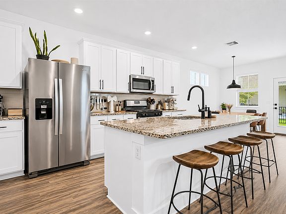 Open kitchen with island, stainless appliances, and pendant lighting