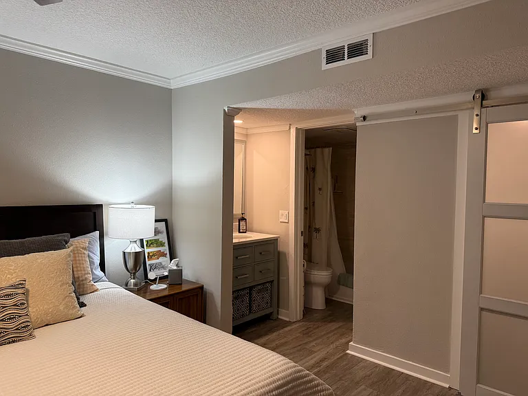 Main bedroom vanity and enclosed bathroom with tub. To the right is the frosted glass barn door to walk-in closet