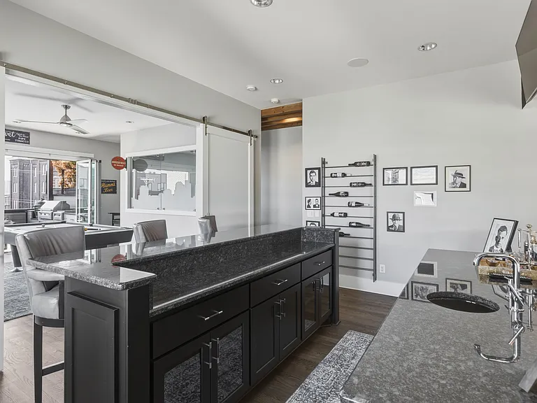 Upstairs mini bar conveniently located just steps from the rooftop patio and game room_perfect for mixing a drink before heading out. Two TVs located above the bar and a wine bottle shelf.