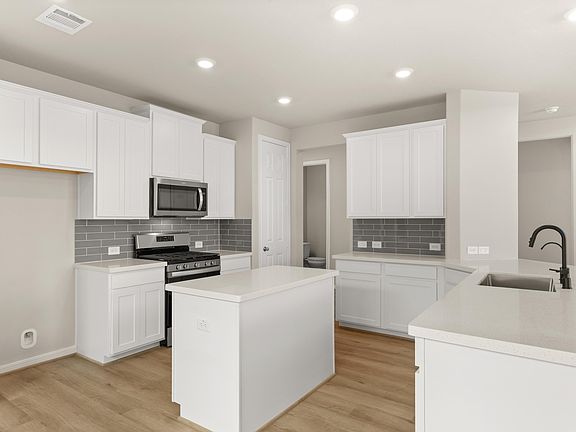 The kitchen features white cabinetry, quartz countertops and a modern subway tile backsplash.
