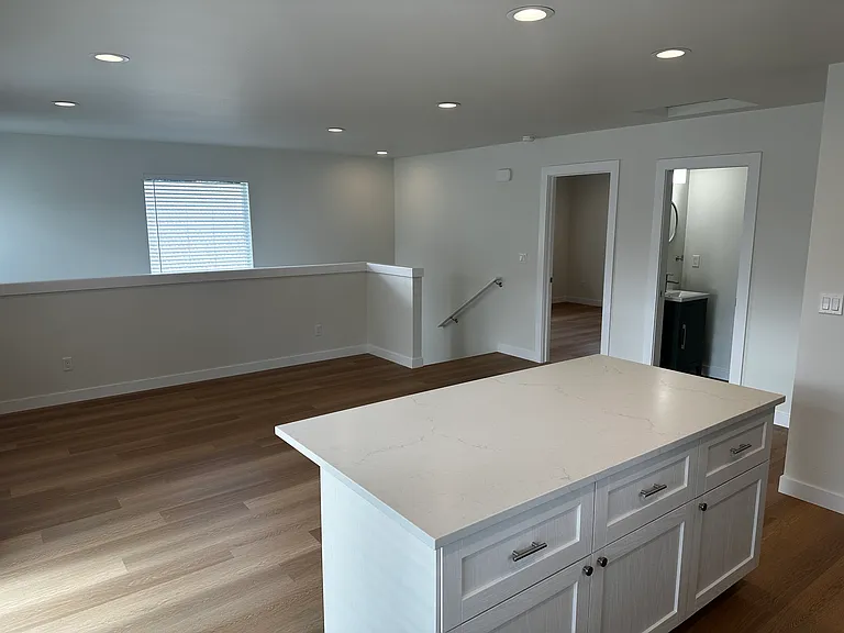 Kitchen island looking across living room with half bath and primary bedroom doors.