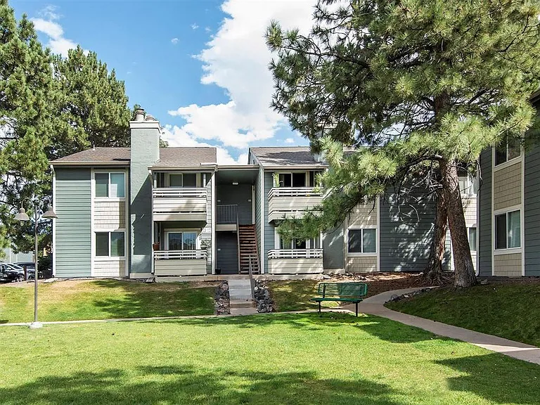 Exterior view of apartments with beautiful greenery and bench seating