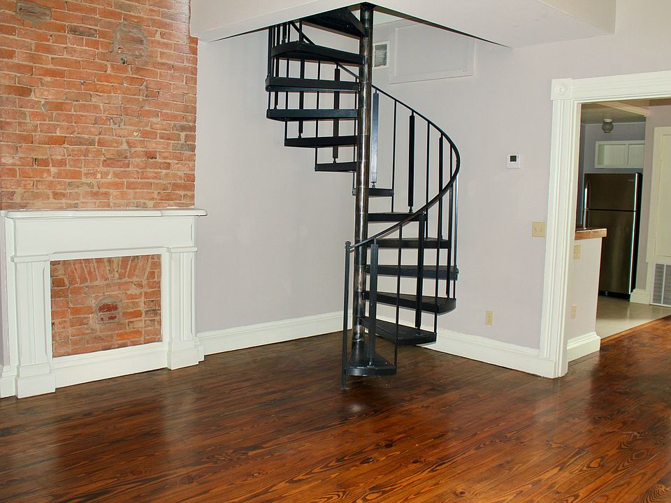 Spacious living room with exposed brick and hardwood floors. Spiral staircase goes to the second floor, where there are two bedrooms, in unit washer and dryer, and one full bathroom. The apartment has central air.