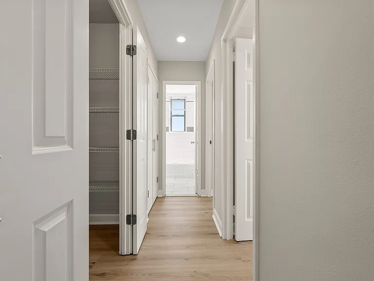 Bright hallway in a modern apartment with wood flooring, expansive hall closet, and a view of a tiled bathroom at Parkside Place, apartments in Cambridge, MA