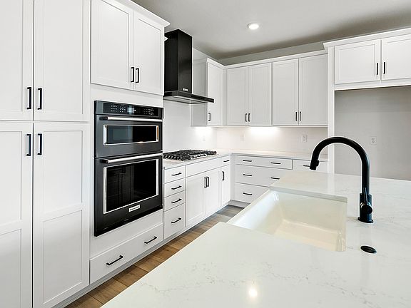 Gourmet kitchen with white quartz counter tops and white cabinetry