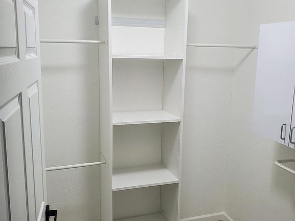 Walk-in master closet with ample storage space; hooks behind the door.