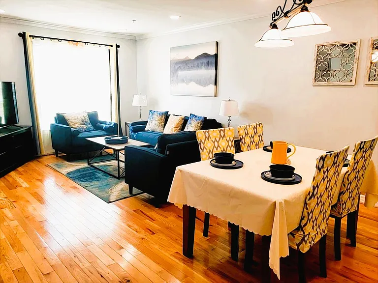 Open living and dining area with hardwood floors, full seating, and a dedicated table for shared meals and gatherings.