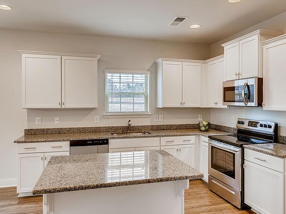 Kitchen features white shaker cabinetry, stainless appliances and granite counters.