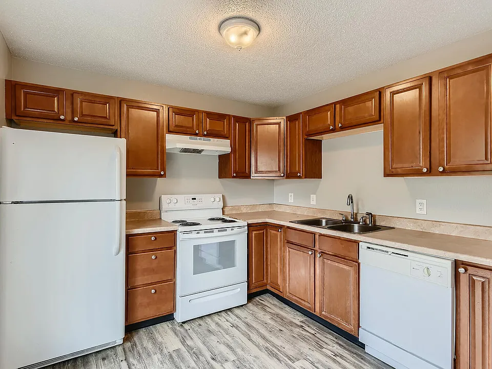 A kitchen with a refrigerator, range oven, dishwasher, and cabinets at Alder Square Rental Townhomes