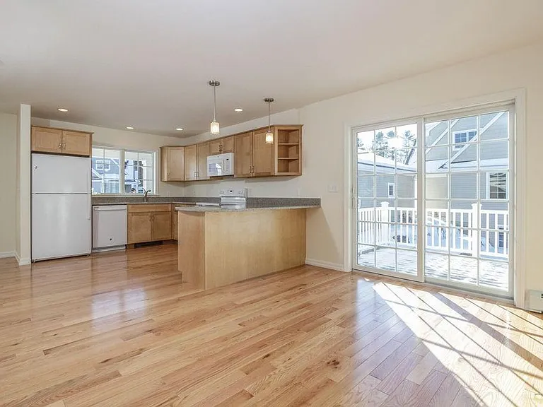 View of kitchen (and front door to left of photo), with dining area and deck. Note all the appliances were replaced with stainless steel in 2020.