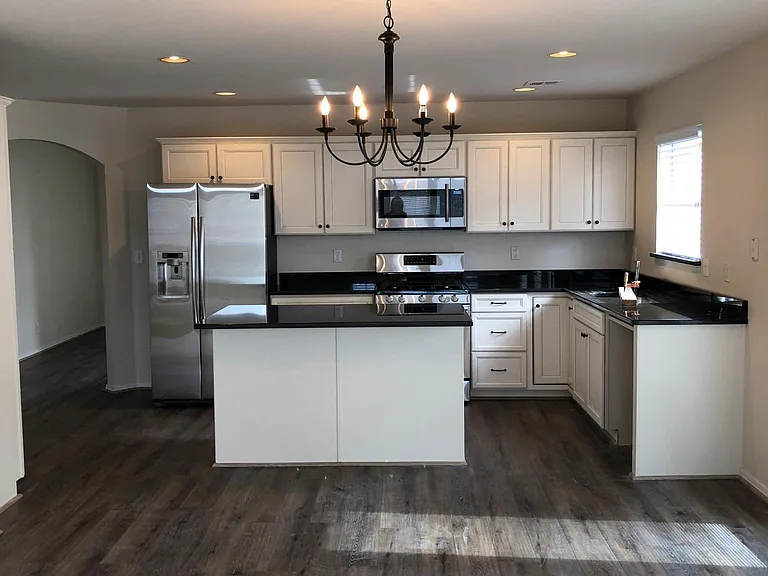 kitchen with island (room for 3 barstools), granite countertops, stainless steel appliances, newer cabinets.
