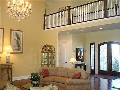 Two story Living Room with handsome balustrade. Schonbek rock crystal chandelier has motorized lift for easy cleaning. Beautiful fireplace with marble and mirror accent creates a stunning impression.