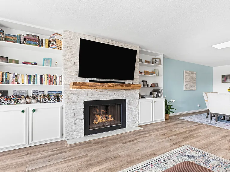 Beautiful gas fireplace with stone facade and built-in bookshelves with storage on the bottom of each
