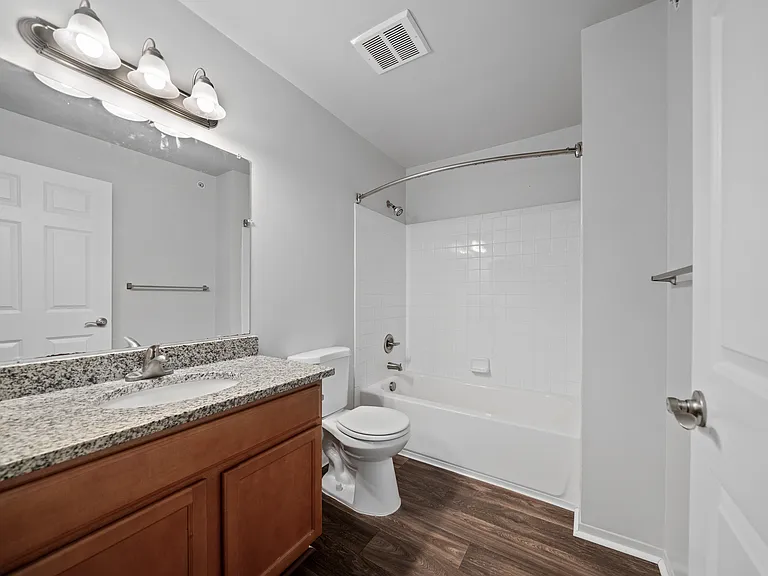 Upgraded bathroom with curved shower rod at Woodland Villa Apartments in Westland, MI.