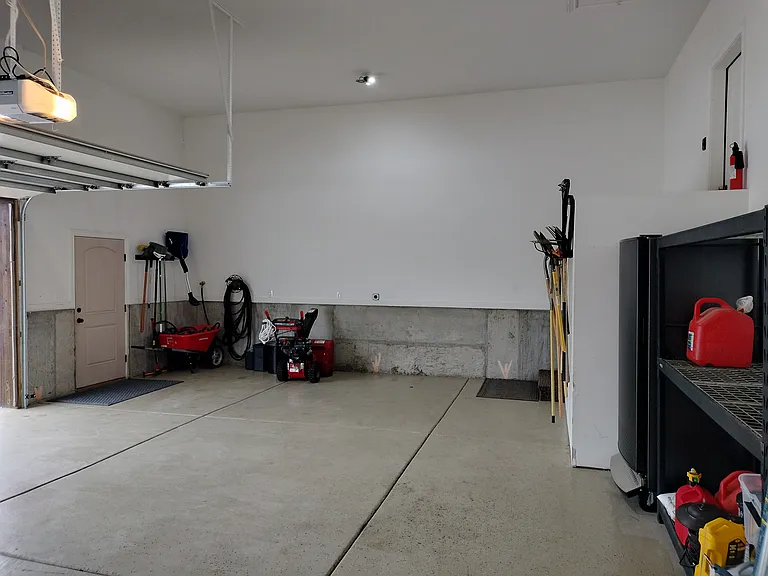 The property includes a two-car garage with extra storage racks, an outdoor freezer, and a 220V plug for convenient electric vehicle charging. Perfect for secure parking and additional storage needs.