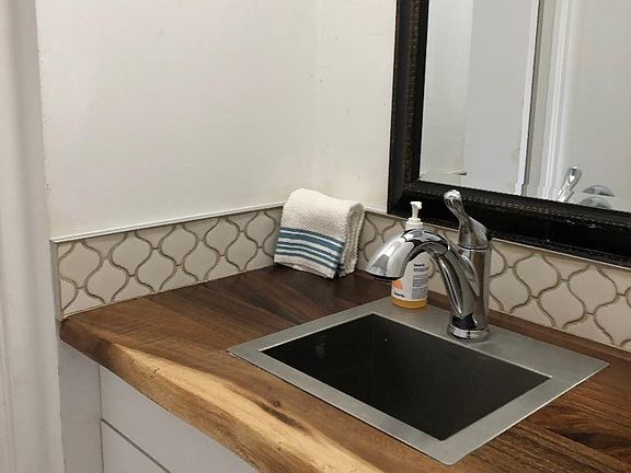 Vanity area with bar sink and disposal.