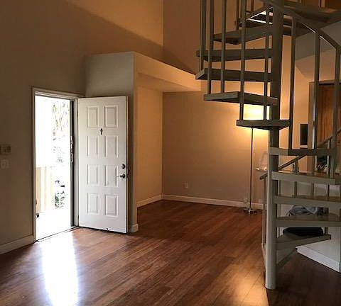 View of main living area with high ceilings and spiral staircase leading up to loft.